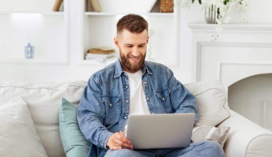 Man Sitting on Couch Using Laptop