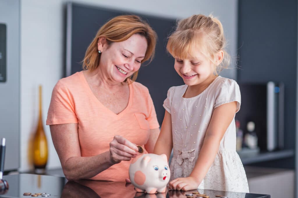 happy mother and daughter with a piggy bank saving